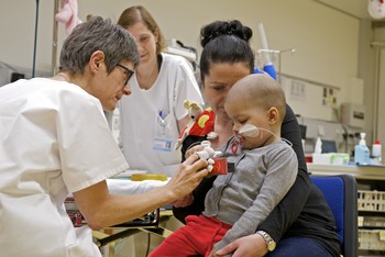 Even small children are irradiated with protons against their cancer at the Center for Proton Therapy ZPT of the Paul Scherrer Institute PSI. Some of them are given anaesthesia. This child sits on its mother's lap and is calmed down by the anaesthetist (on the left in the picture) with a finger puppet game before the treatment starts. 