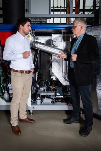 Dominik Ebi (left) und Peter Jansohn in front of the mini gas turbine at PSI. (Photo: Paul Scherrer Institute/Mahir Dzambegovic)