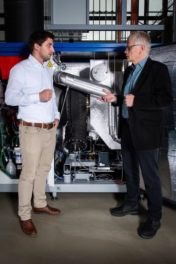 Dominik Ebi (links) und Peter Jansohn vor der Minigasturbine am PSI. (Foto: Paul Scherrer Institut/Mahir Dzambegovic)