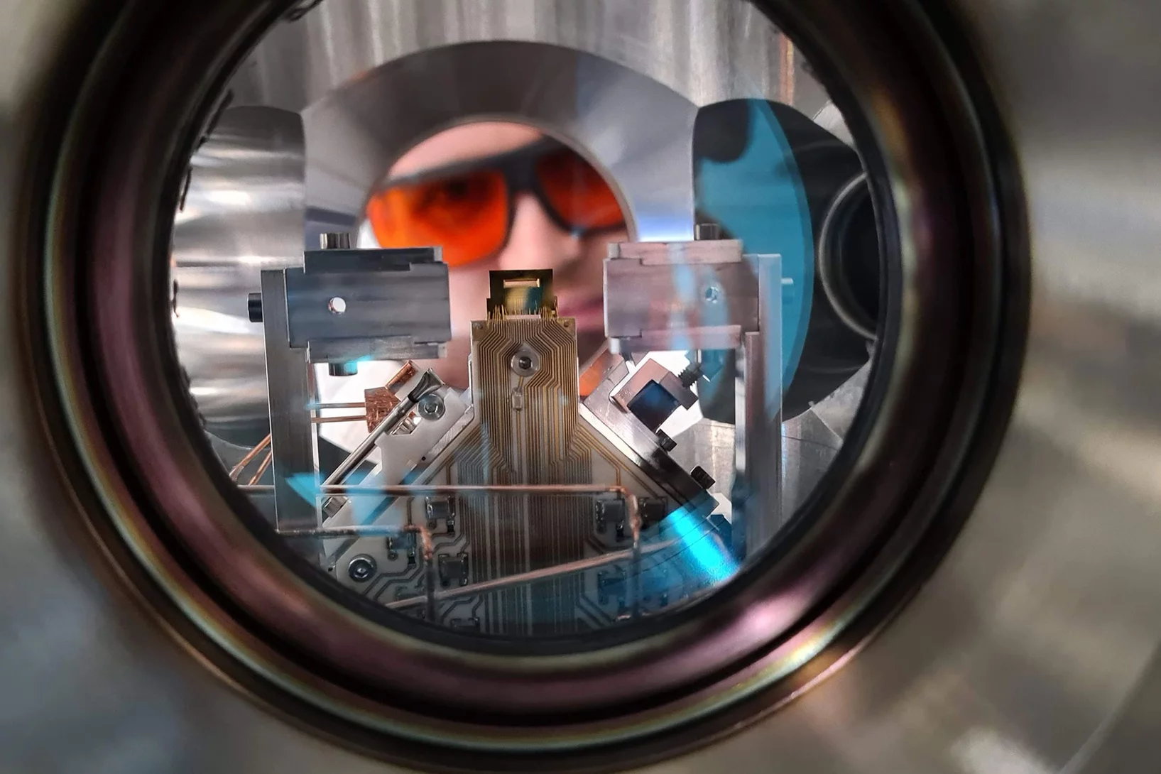 Ein Forscher blickt in die Ultrahochvakuumkammer eines Quantencomputers am PSI, der mit gefangenen Ionen arbeitet. 