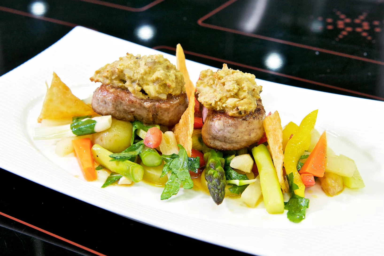 Schweinsfiletmedaillons mit Pilz-Senfhaube auf lauwarmem Gemüsesalat an Tomaten-Rucola-Vinaigrette