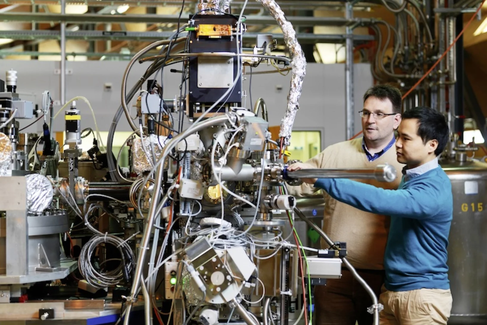 PSI scientist Thorsten Schmitt (left) and post-doc Kejin Zhou (right) at the RIXS measuring station of the ADRESS beamline at SLS, where they are inserting a sample into the measuring apparatus. Here, X-rays are used for investigating materials with very high precision. (Photo: Scanderbeg Sauer Photography)